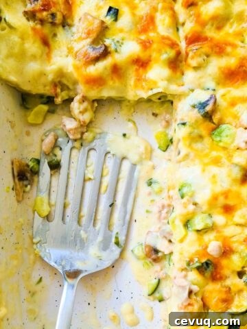 A tray of creamy lasagna with a spatula