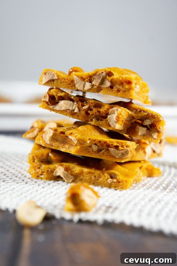 Stacked peanut brittle on a white burlap strip with scattered brittle shards around it