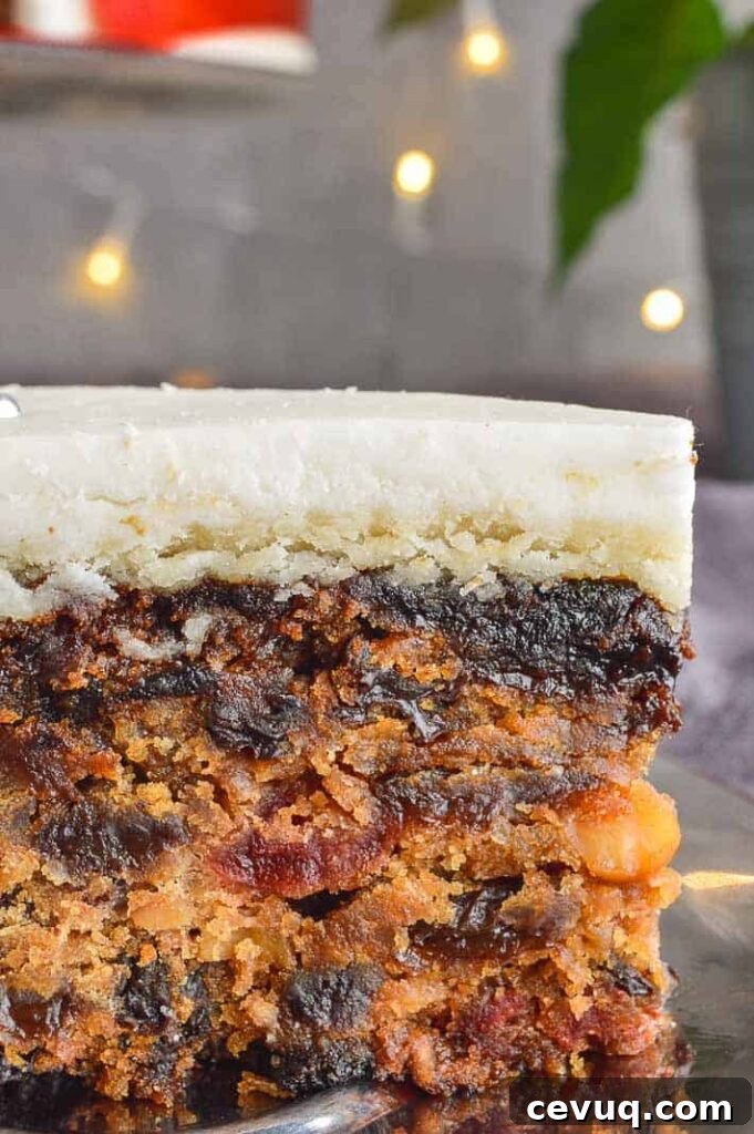 Irish-Style Vegan Christmas Cake Recipe 3 A cut away of a dark fruit cake with a leayer of marzipan and white icing
