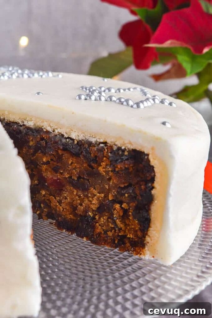 Irish-Style Vegan Christmas Cake Recipe 8 A dark fruit cake with a slice cut out and a layer of marzipan and royal frosting