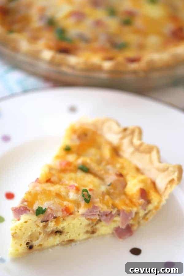 Classic Ham and Cheese Quiche with Flaky Crust 4 A plate with a slice of egg and ham quiche.