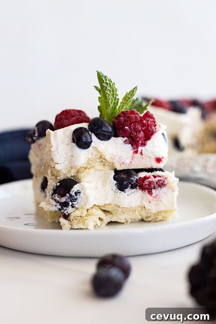 No Bake Berry Icebox Cake with Fresh Berries 2 Piece of berry icebox cake on a white plate with a mint garnish.