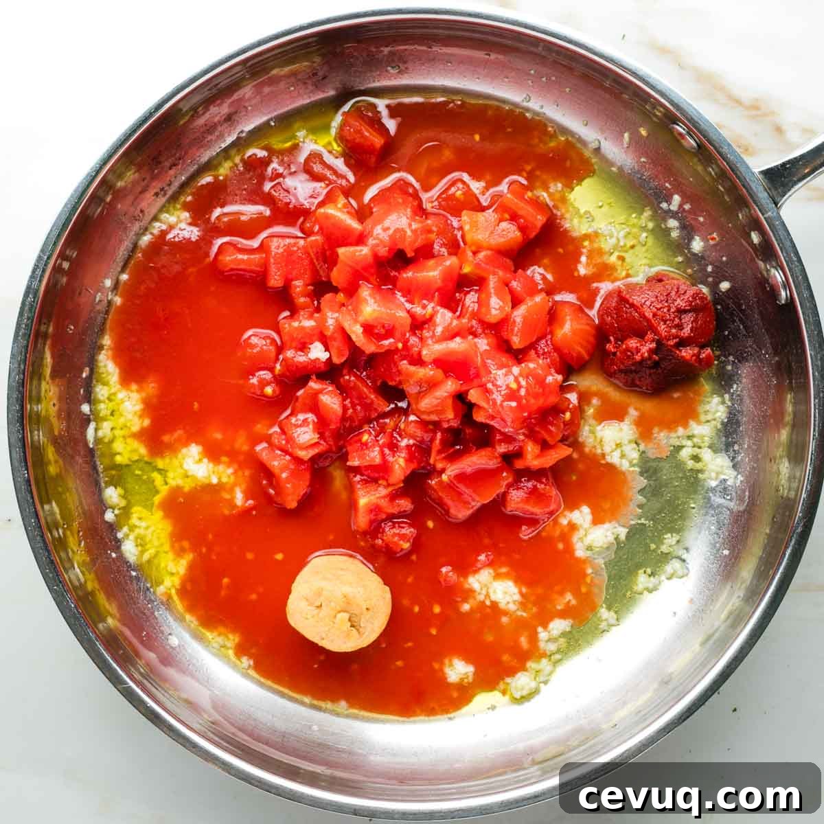 Vegan White Bean Puttanesca Pasta 6 Diced tomatoes, tomato paste and miso paste in a skillet with garlic and olive oil.