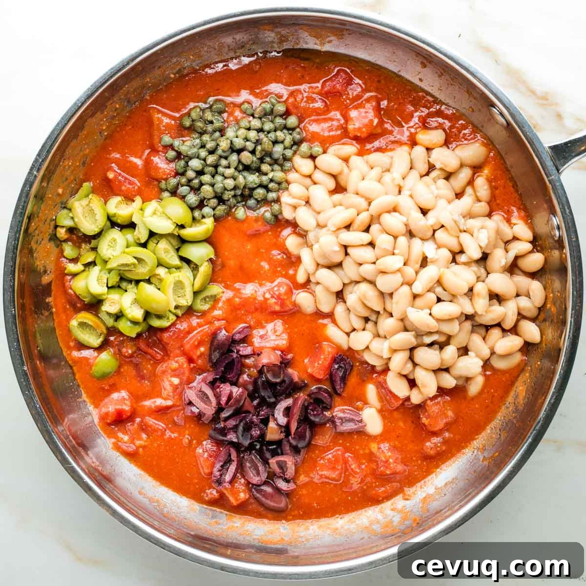 Vegan White Bean Puttanesca Pasta 7 Saucy diced tomatoes with chopped olives, capers and white beans in a skillet.