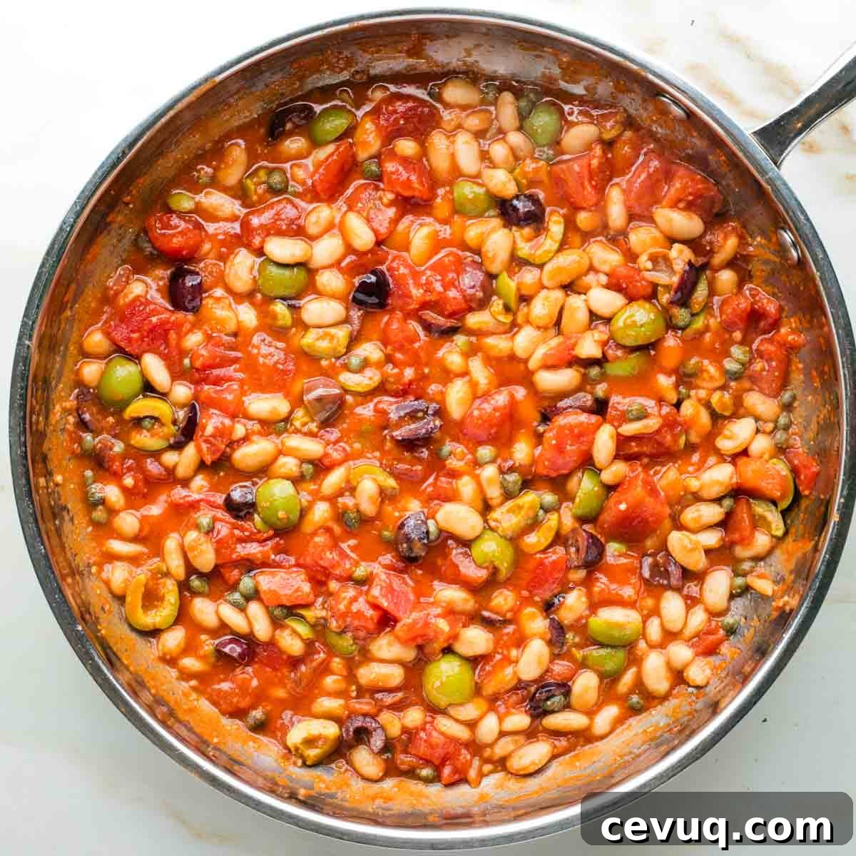 Vegan White Bean Puttanesca Pasta 8 Making puttanesca sauce in a skillet with tomatoes, olives, capers and white beans.