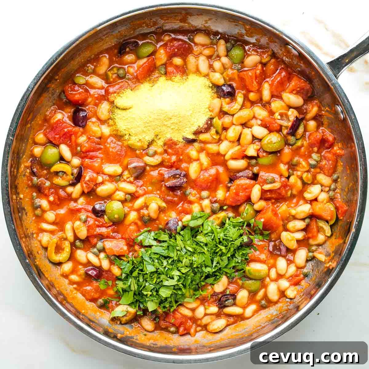 Vegan White Bean Puttanesca Pasta 9 Nutritional yeast and fresh chopped parsley on top of a chunky puttanesca sauce with white beans.