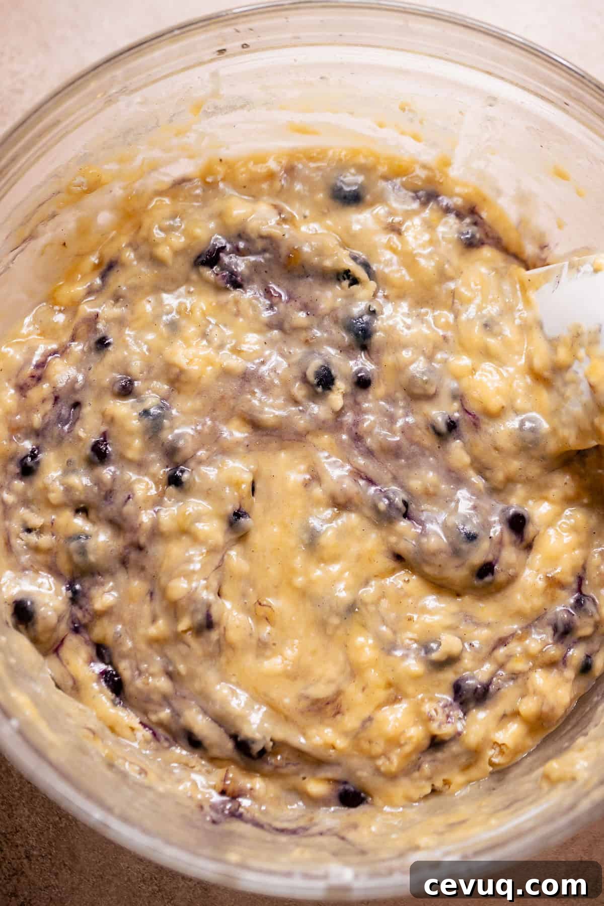 Thick banana bread batter with blueberries folded into the mixture.