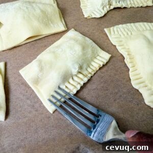 Flaky Apple Hand Pies with Puff Pastry 9 Fork crimping apple hand pie edges.