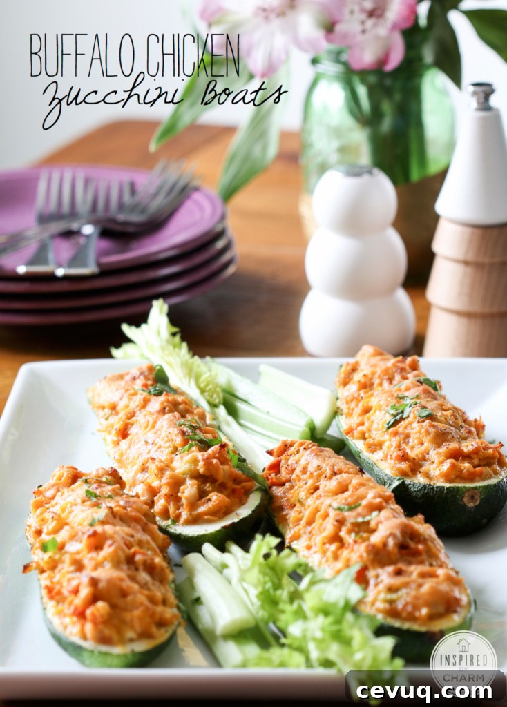 Buffalo Chicken Stuffed Zucchini Boats on a serving dish with plates in the background.