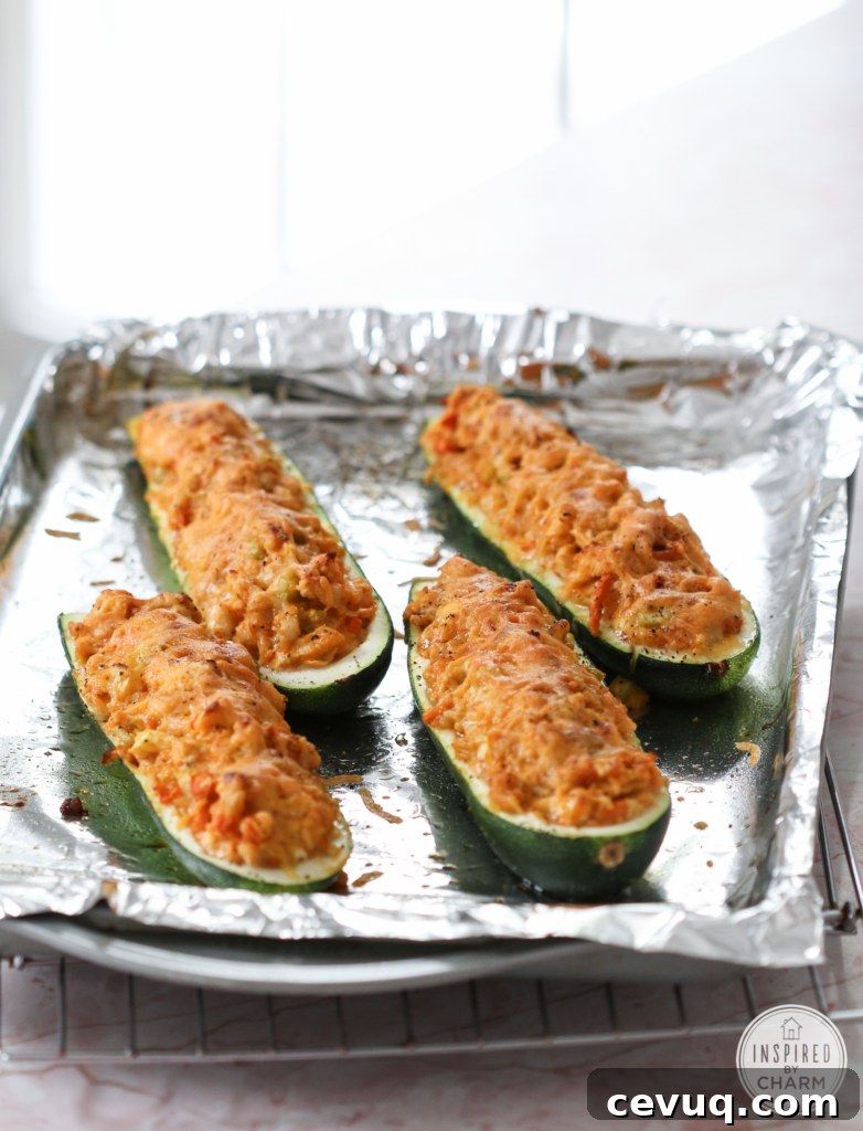 Baked Buffalo Chicken Stuffed Zucchini Boats on a baking sheet with foil.
