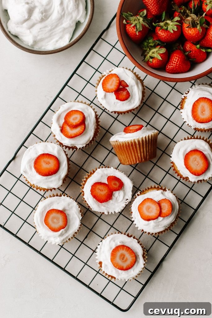 Paleo Strawberry Shortcake Cupcakes Recipe 5 strawberry shortcake cupcakes on a cooling rack with a bowl of strawberries and bowl of cool whip