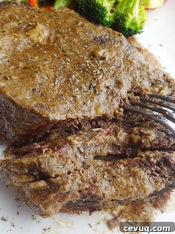 Cooked beef roast on platter with fork.