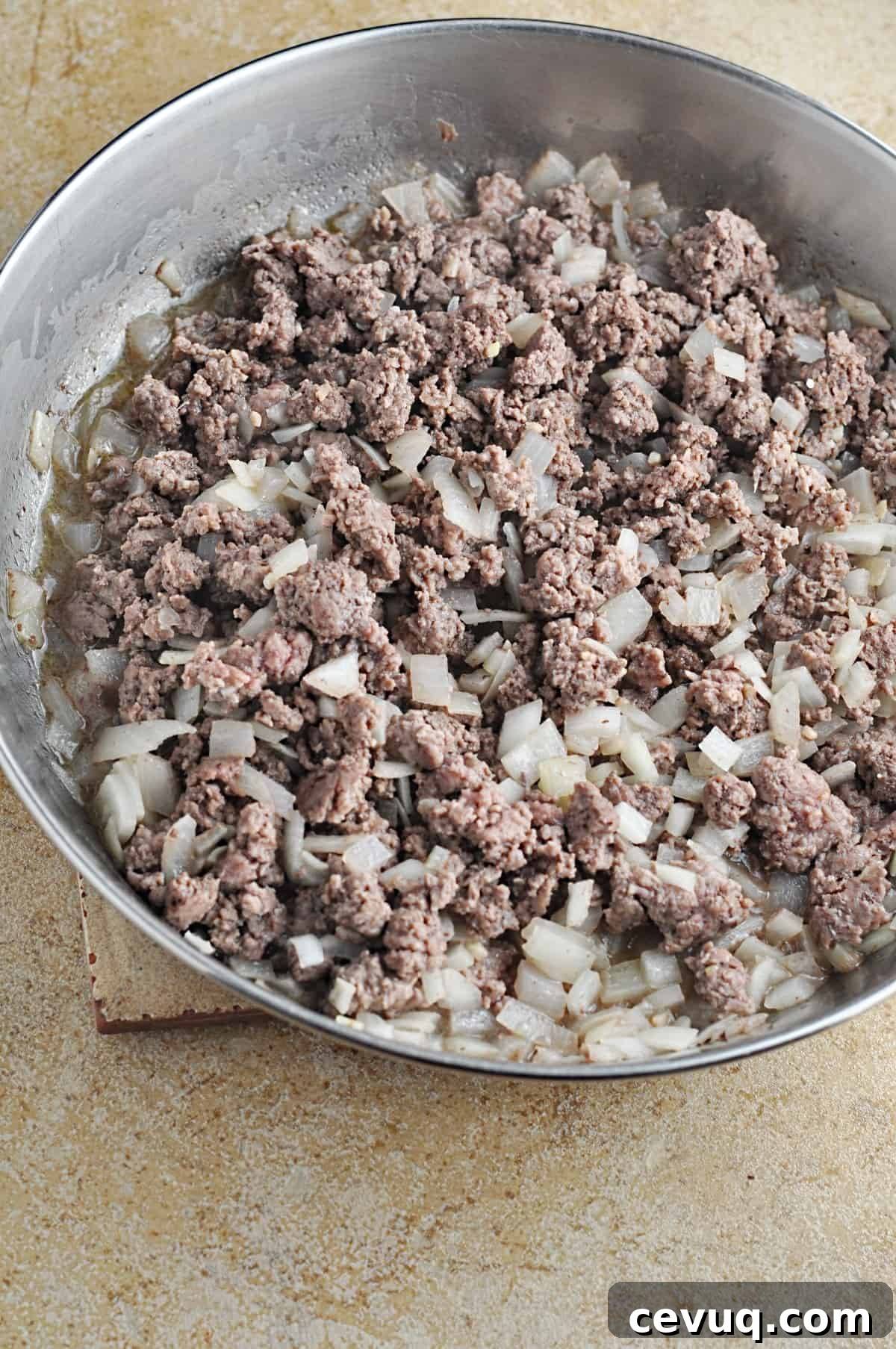 Cooked ground beef and chopped onions in skillet.