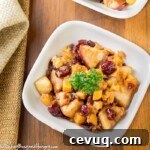 Overhead shot of two white bowls of butternut squash and apples on a wooden surface with a tan cloth on the side.