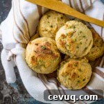 Overhead view of biscuits in a bowl wrapped in a striped towel with a wooden spoon.