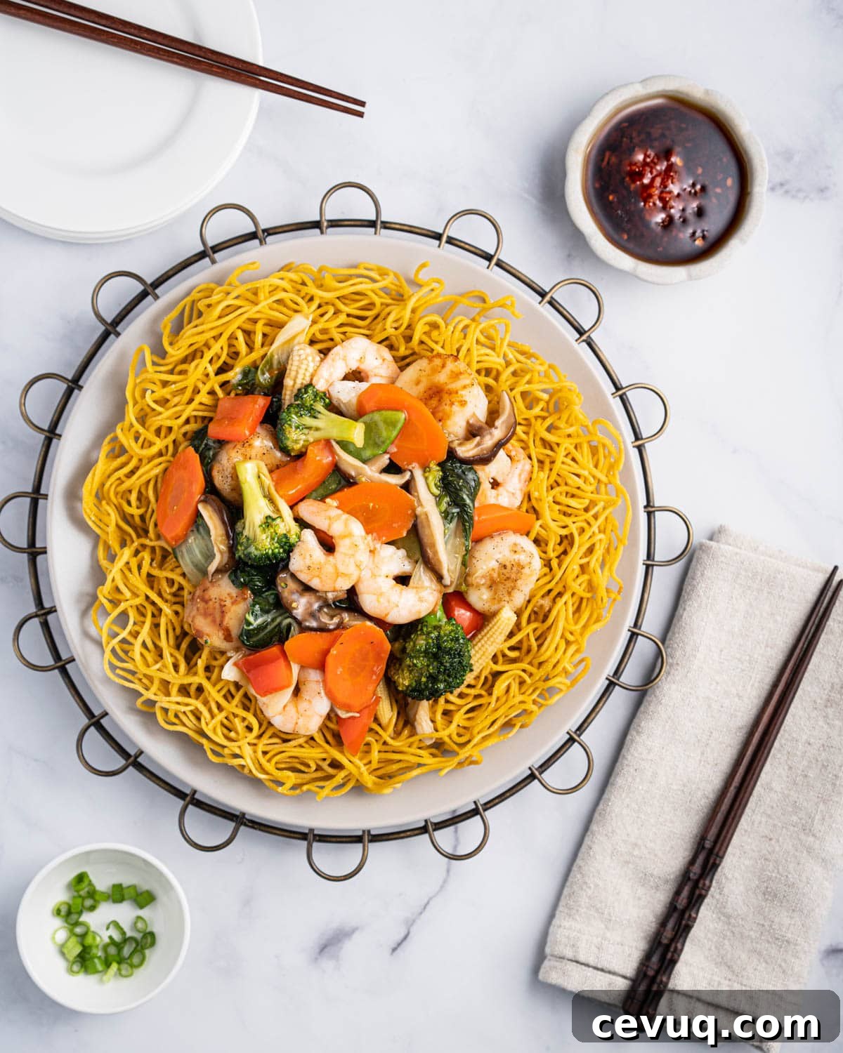 Crispy Pan-Fried Seafood Noodles with Vegetables 10 Plate of mi xao gion with stir fried shrimp, scallops, carrots, broccoli, baby corn, baby bok choy, mushrooms, red bell peppers, and onions.