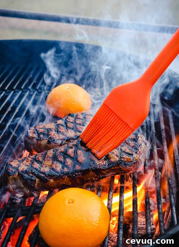 Grilled Bourbon Molasses Marinated Steak Recipe 6 Basting strip steaks on a grill with orange halves