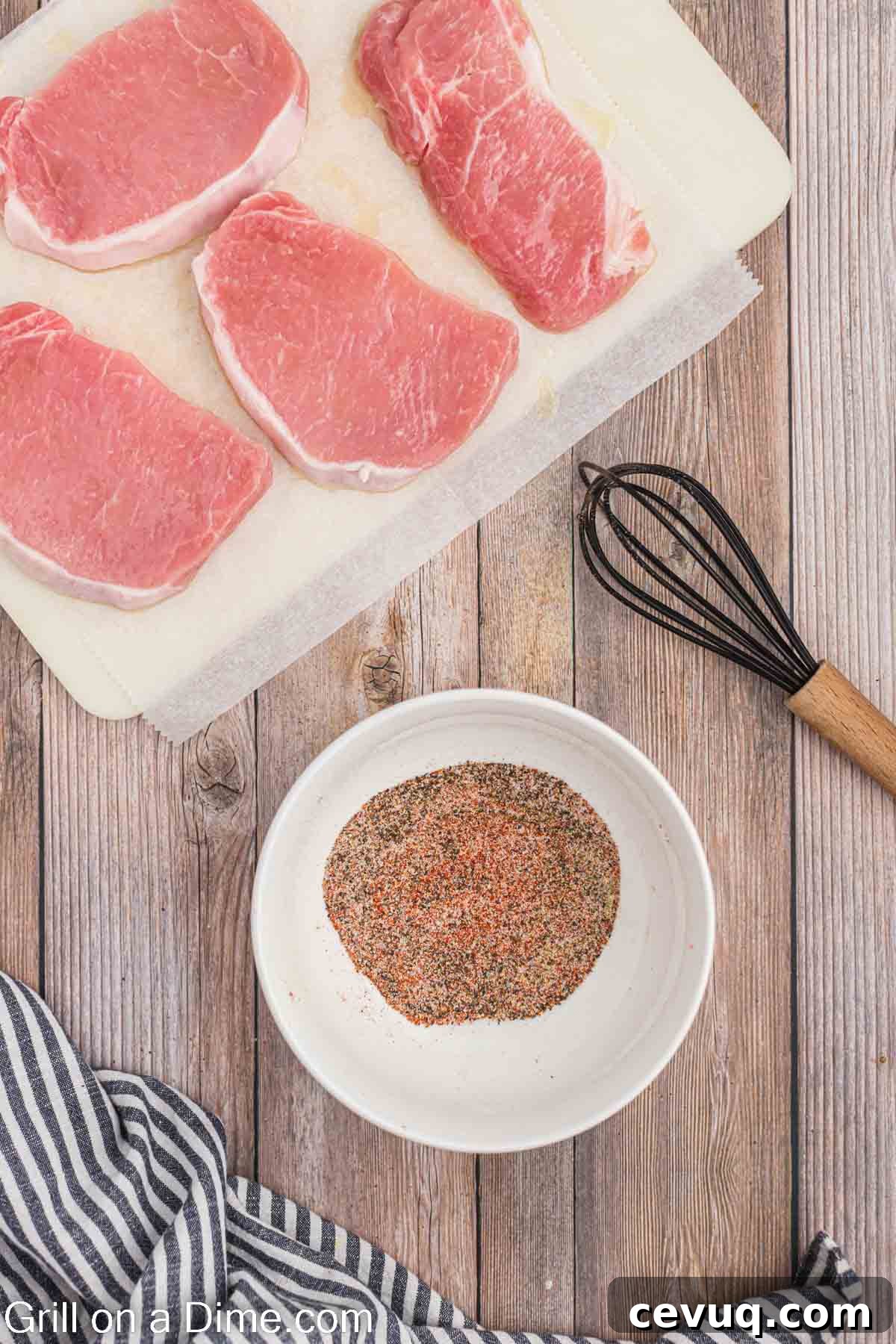 Uncooked pork chops on a cutting board with a small bowl of seasoning blend with a whisk