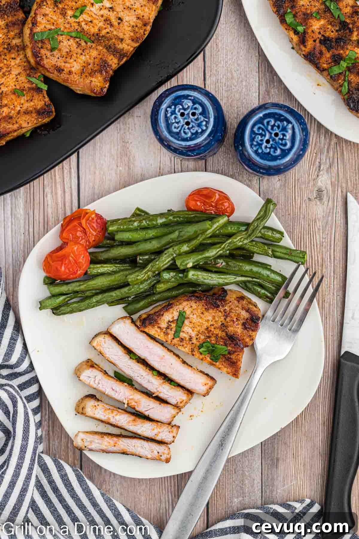 Grilled Boneless pork chops on a plate with green beans and cherry tomatoes