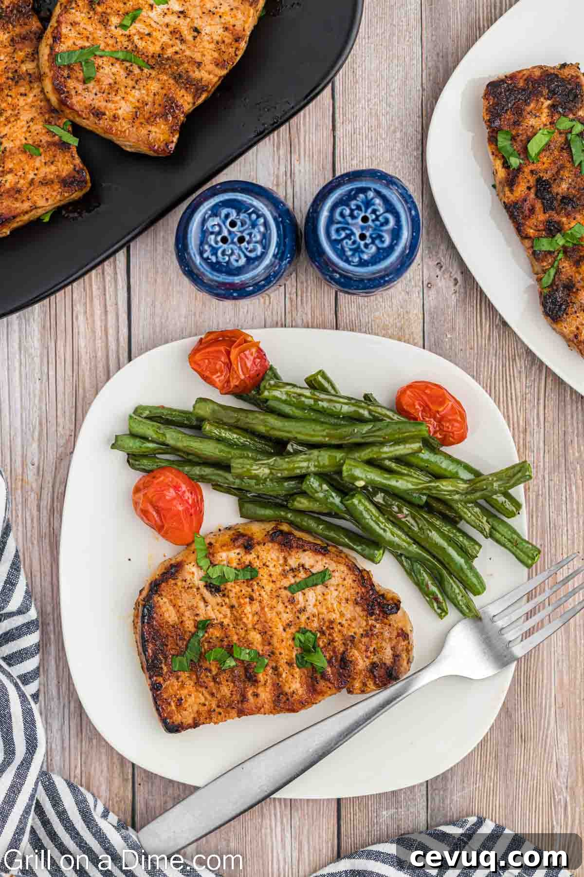 Grilled Boneless pork chops on a plate with green beans and cherry tomatoes