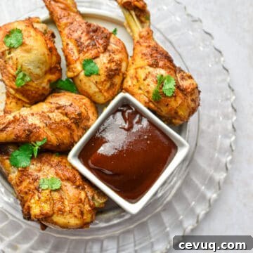 Tender, Juicy Instant Pot Chicken Drumsticks Recipe 11 The Instant Pot Chicken Legs are on a glass plate with a bowl of barbecue sauce.
