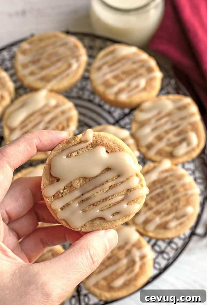 hand holding a paleo cinnamon roll cookie showing the top with icing 