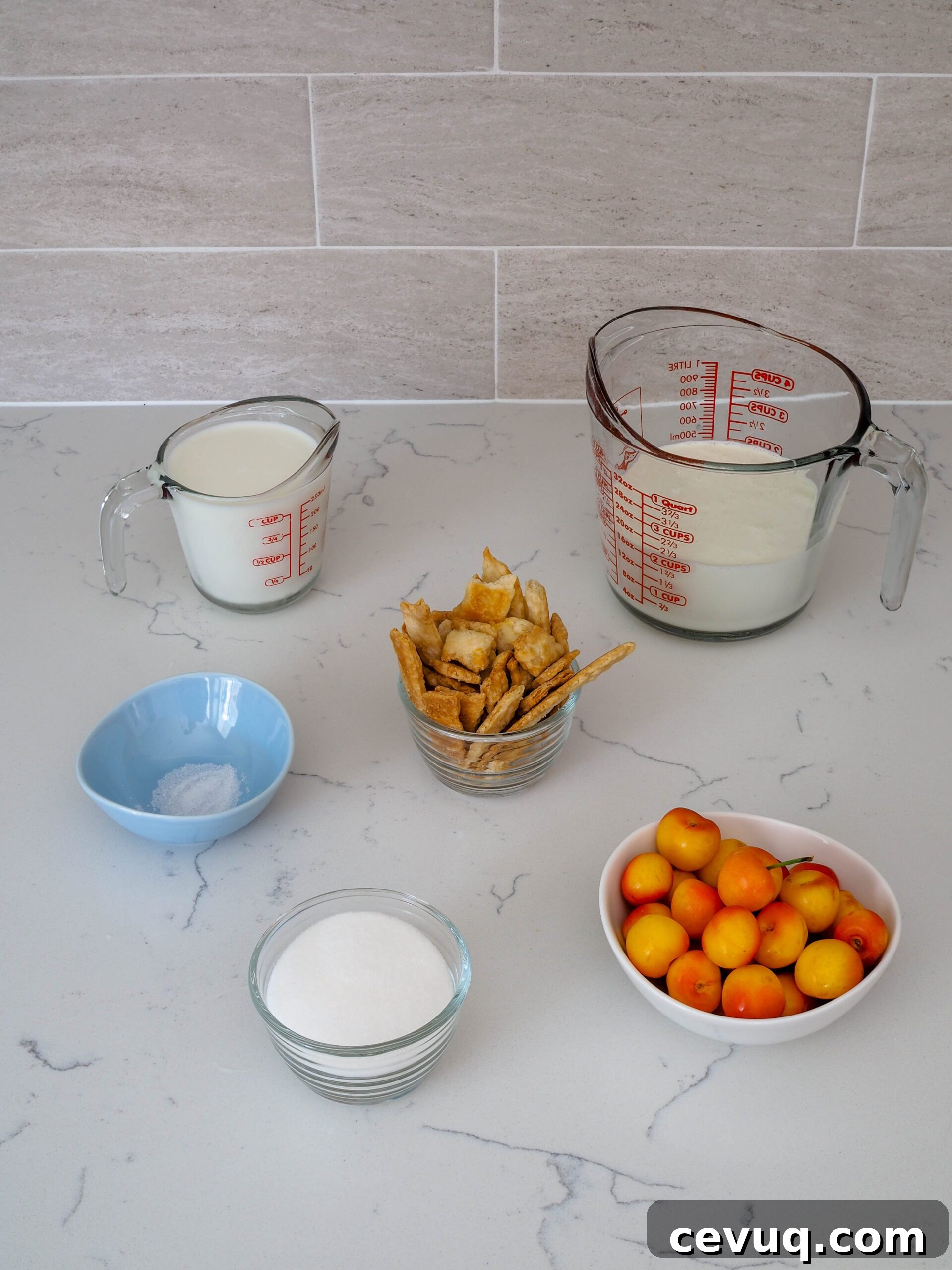 Cherries, sugar, salt, milk, heavy cream, and pie crust arranged on a counter.