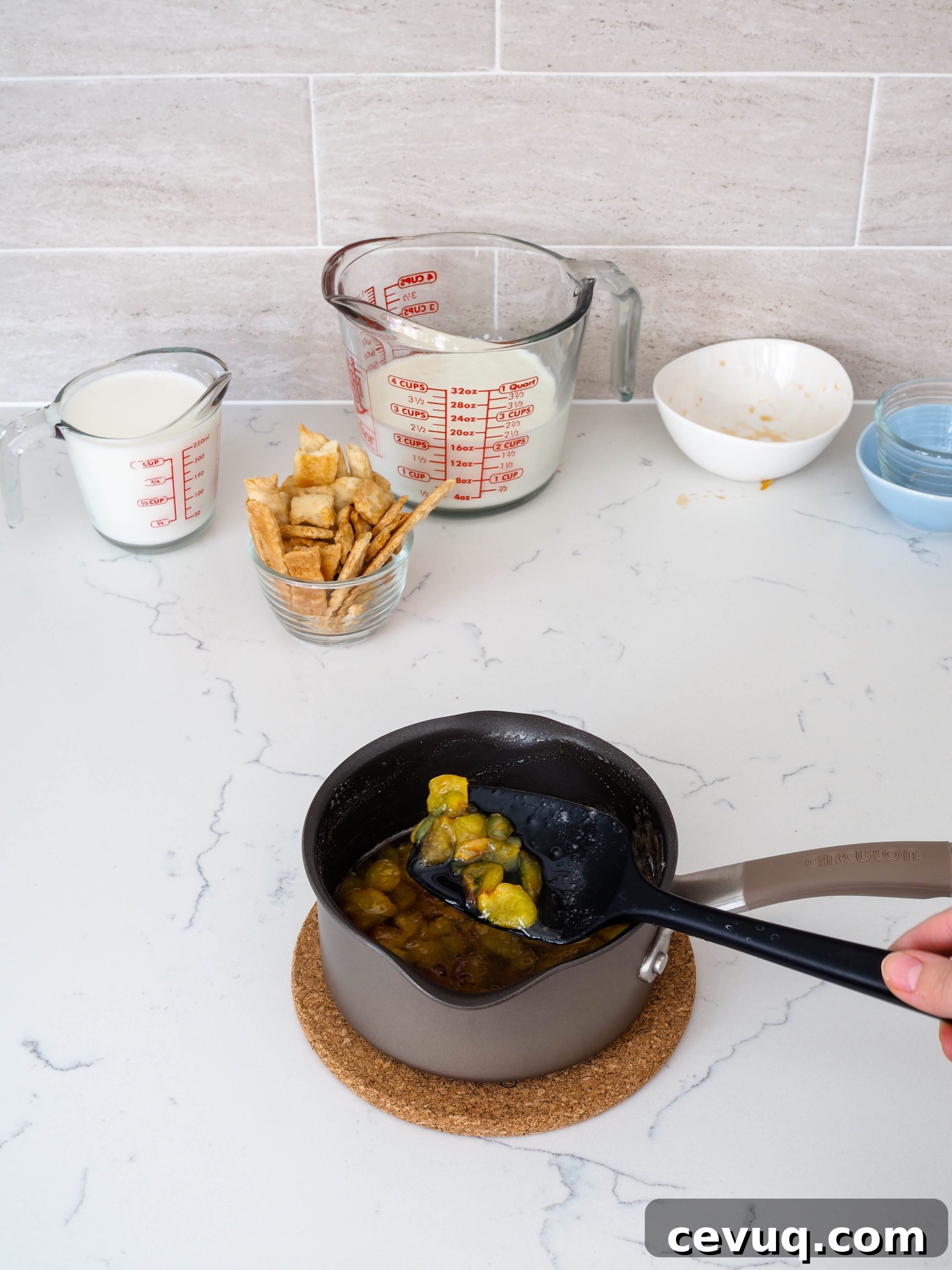 A spatula raises some cherries out of a homemade syrup in a small saucepan.