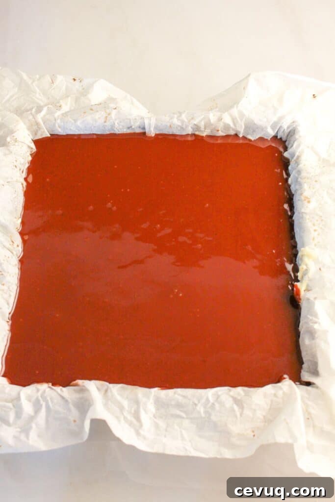 Ganache being spread on top of dessert in a baking pan.