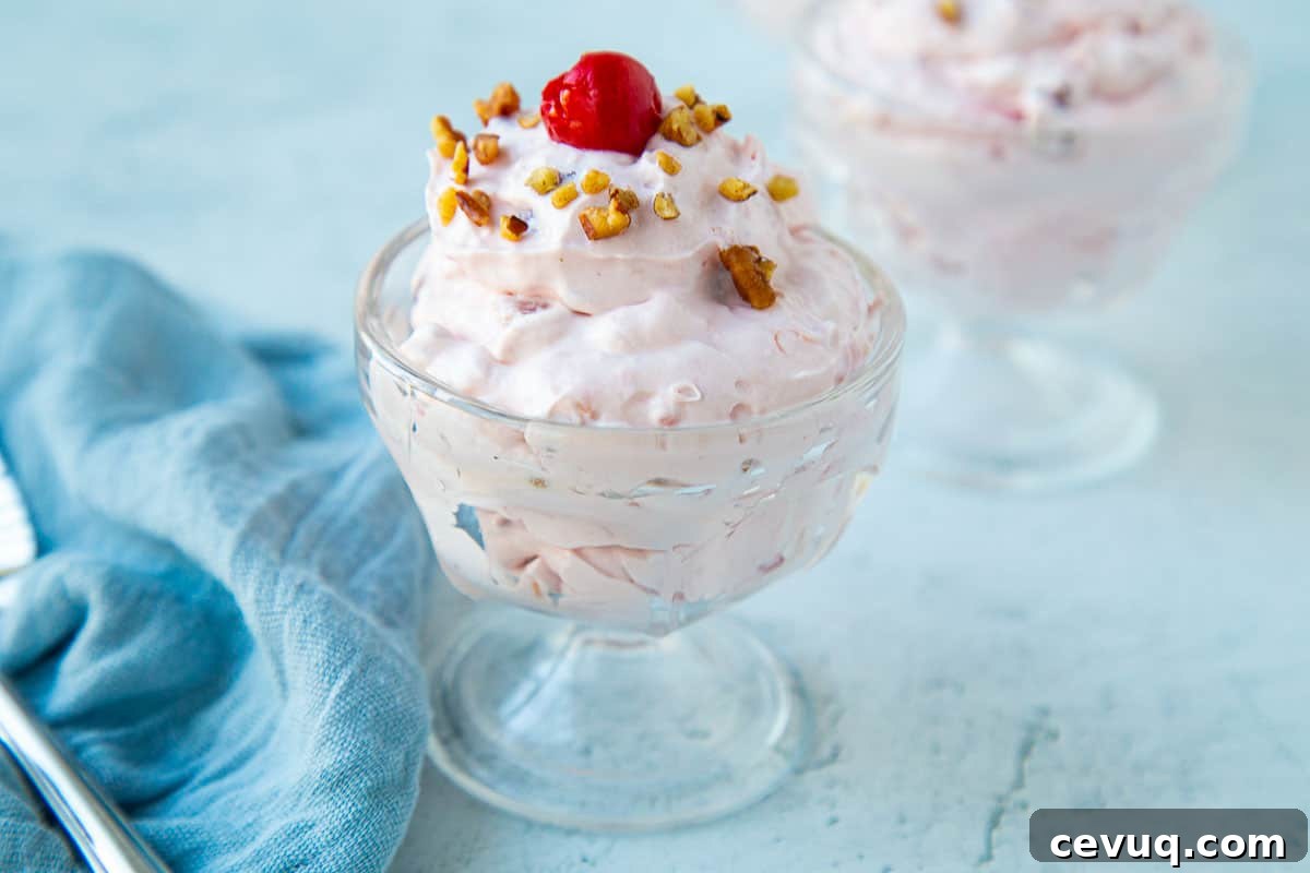 mini glass parfait dish filled with cherry salad, topped with pecans and a cherry.