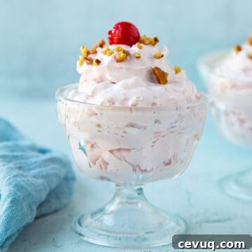 cherry salad topped with a cherry and chopped pecans in a mini glass parfait dish.