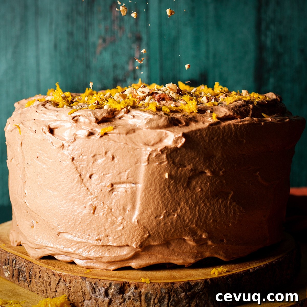 Sprinkling chopped almonds over the top of a chocolate spice cake covered in chocolate orange buttercream.