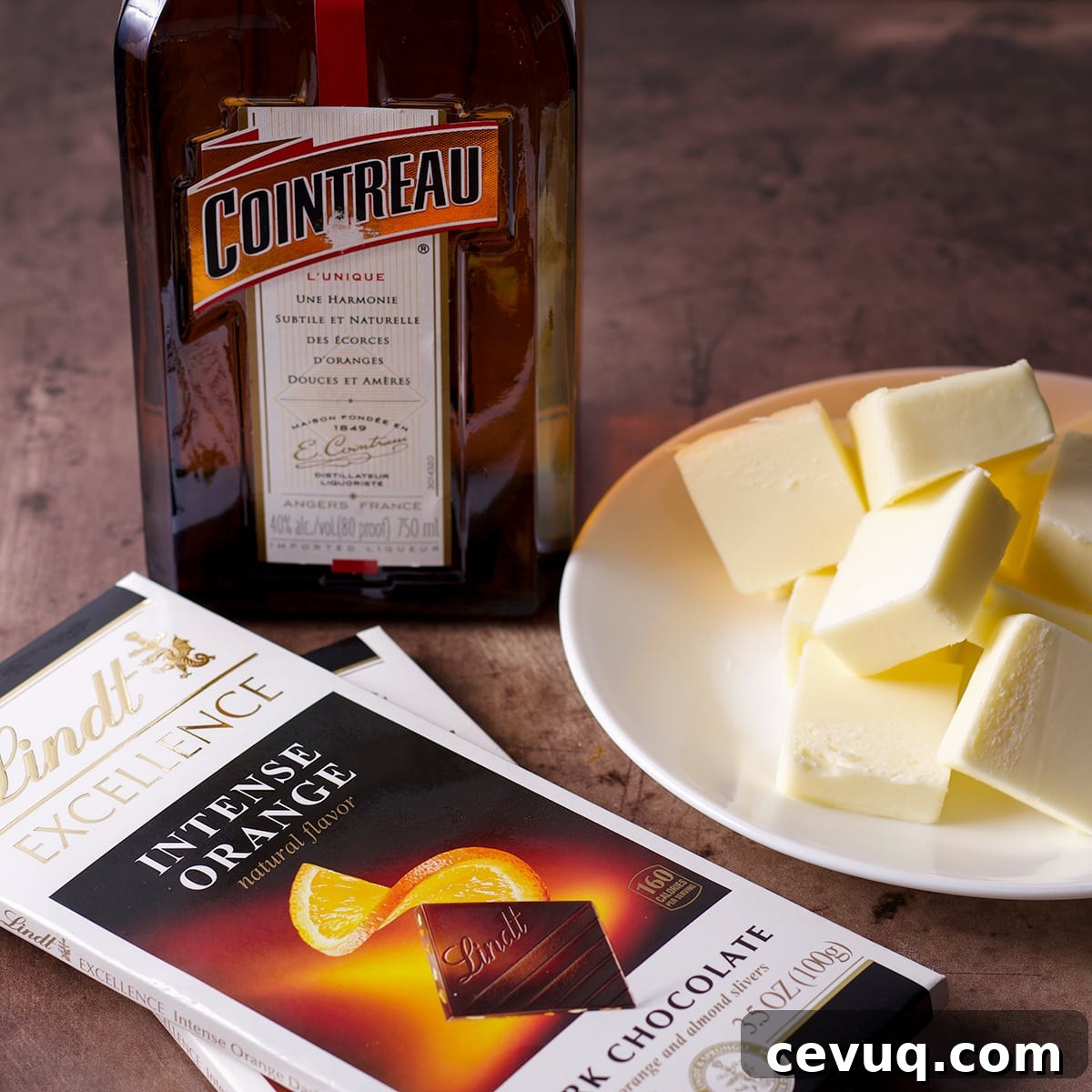 The ingredients to make chocolate orange buttercream, orange liquor, butter, and orange flavored chocolate, sitting on a countertop.