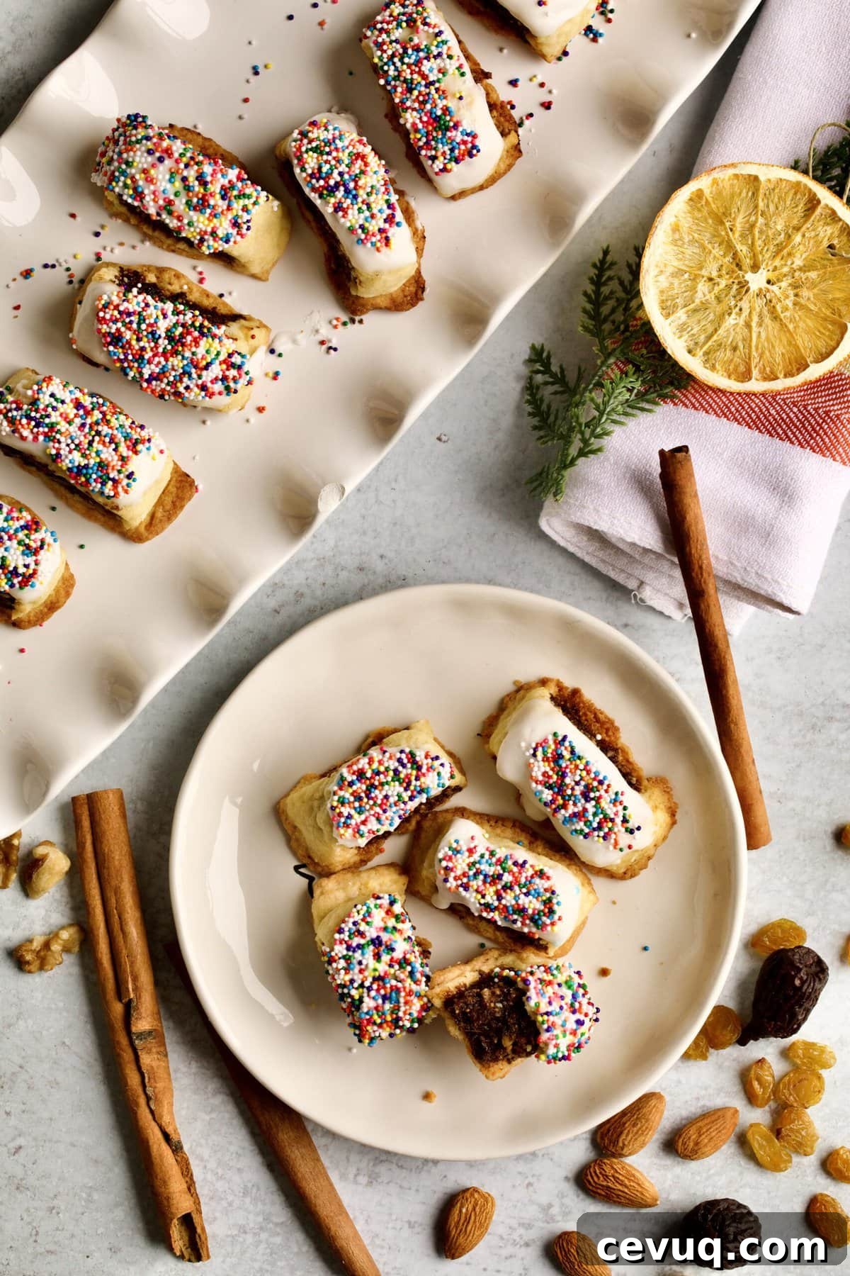 fig cookies with glaze and sprinkles on a plate. One cookie cut in half. ingredients in the background.