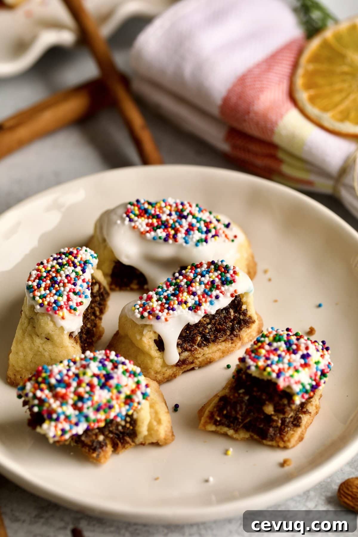 fig cookies with glaze and sprinkles on a plate. One cookie cut in half.