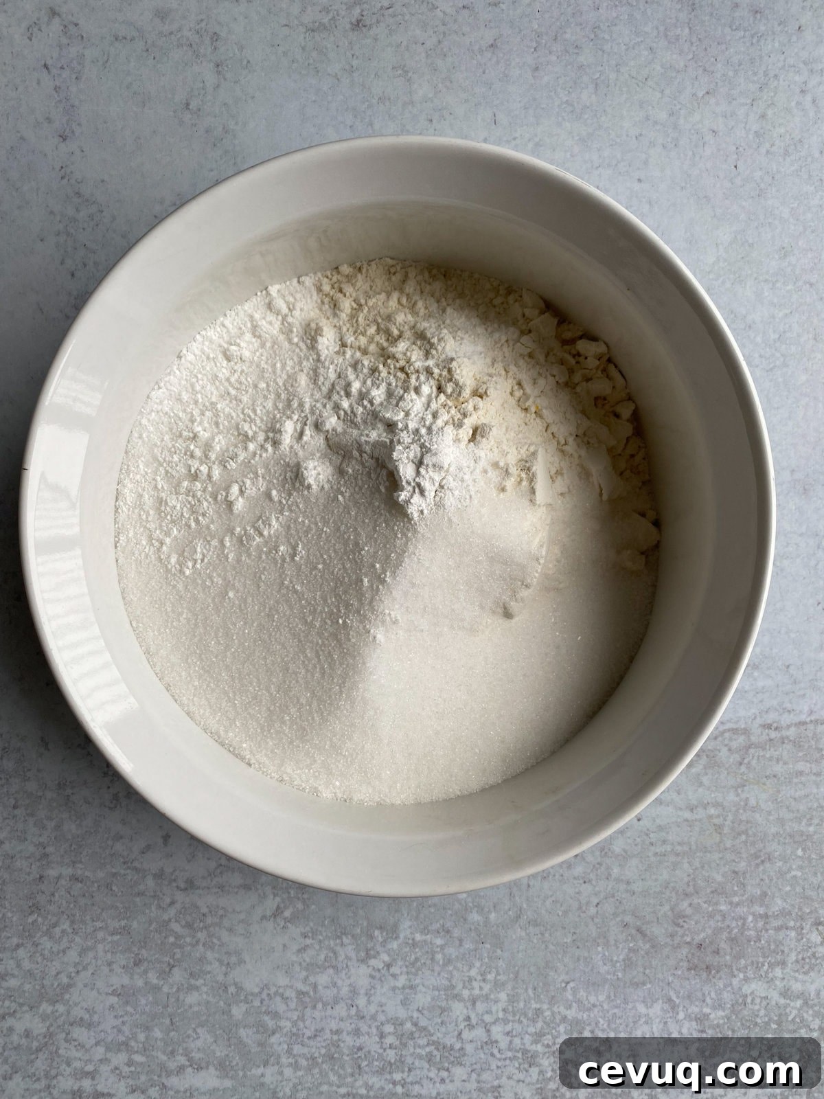 Adding dry ingredients to a bowl and mixing.