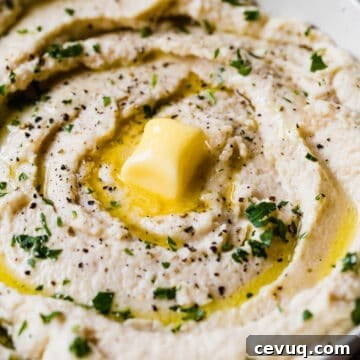 prepared mashed cauliflower in a serving bowl with a glob of butter on top