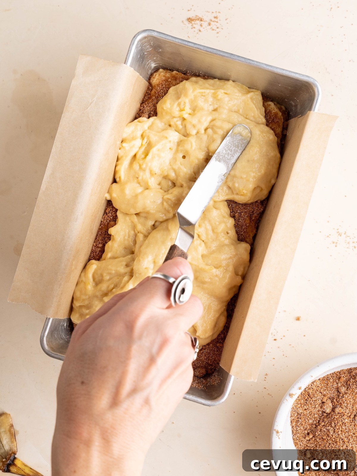 Spreading banana batter over cinnamon sugar mixture