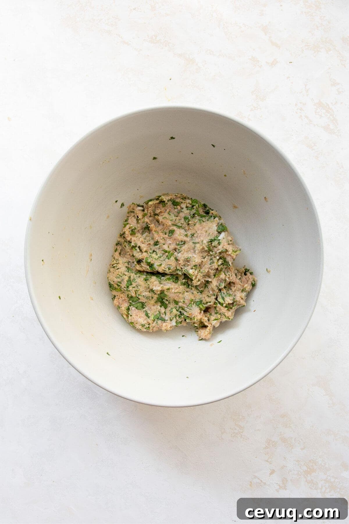 Raw chicken meatball mixture in a mixing bowl.