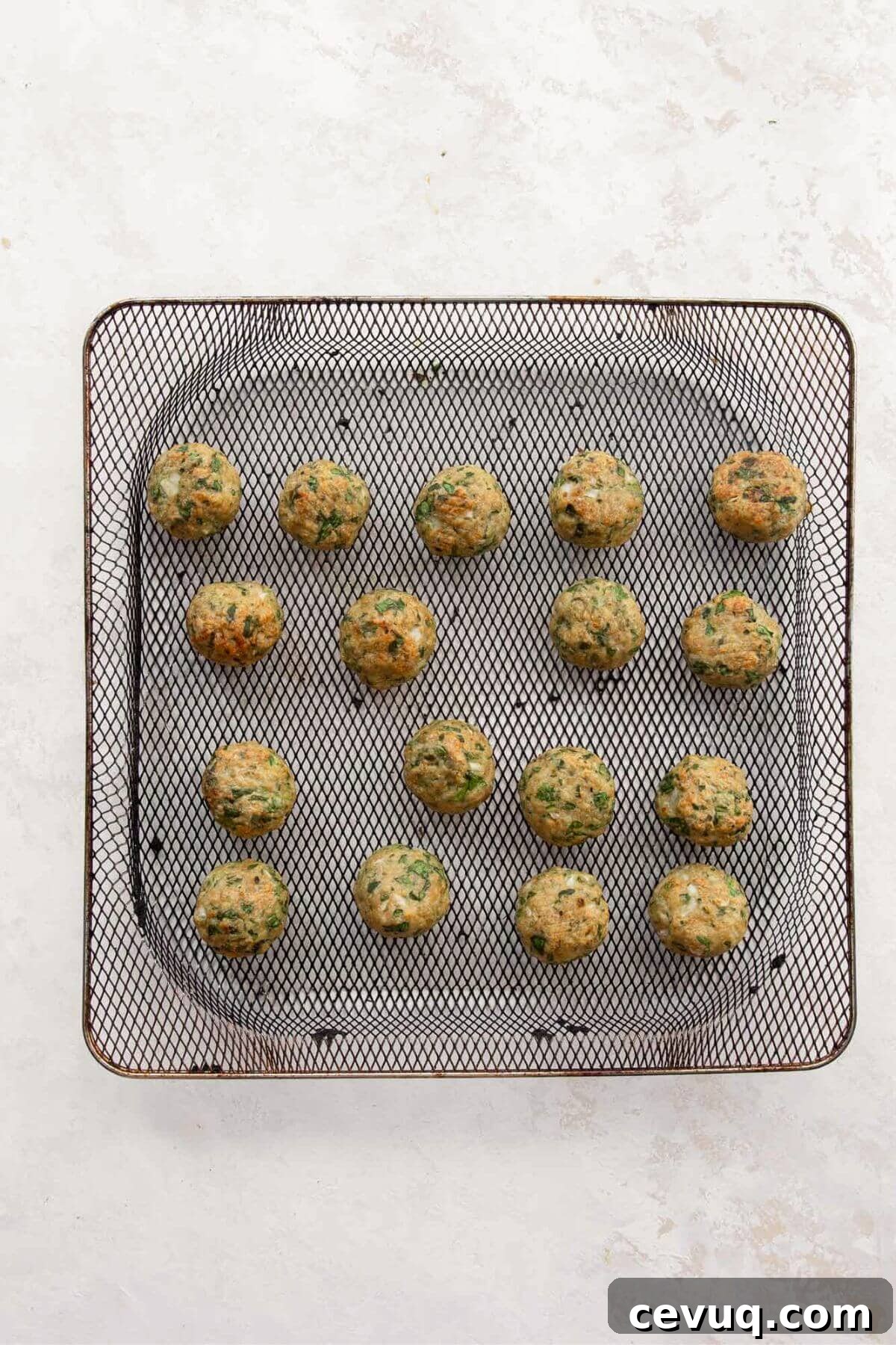 Golden brown cooked chicken meatballs in an air fryer basket, crispy on the outside and ready to serve.