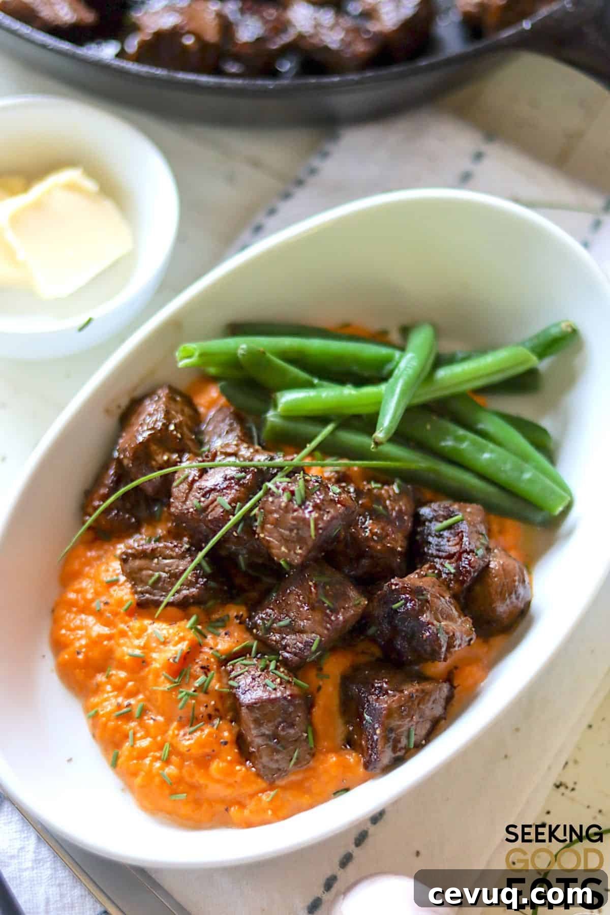 Seated steak bites served with green beans and sauce.