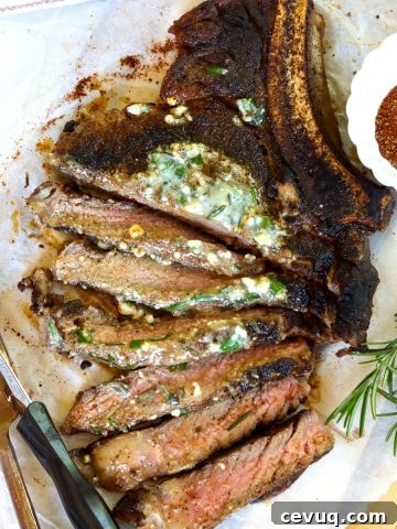 A medium-rare sliced cowboy ribeye steak served on a wooden board.