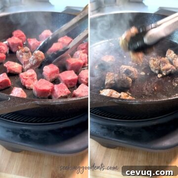 Searing steak bites in a cast iron skillet.