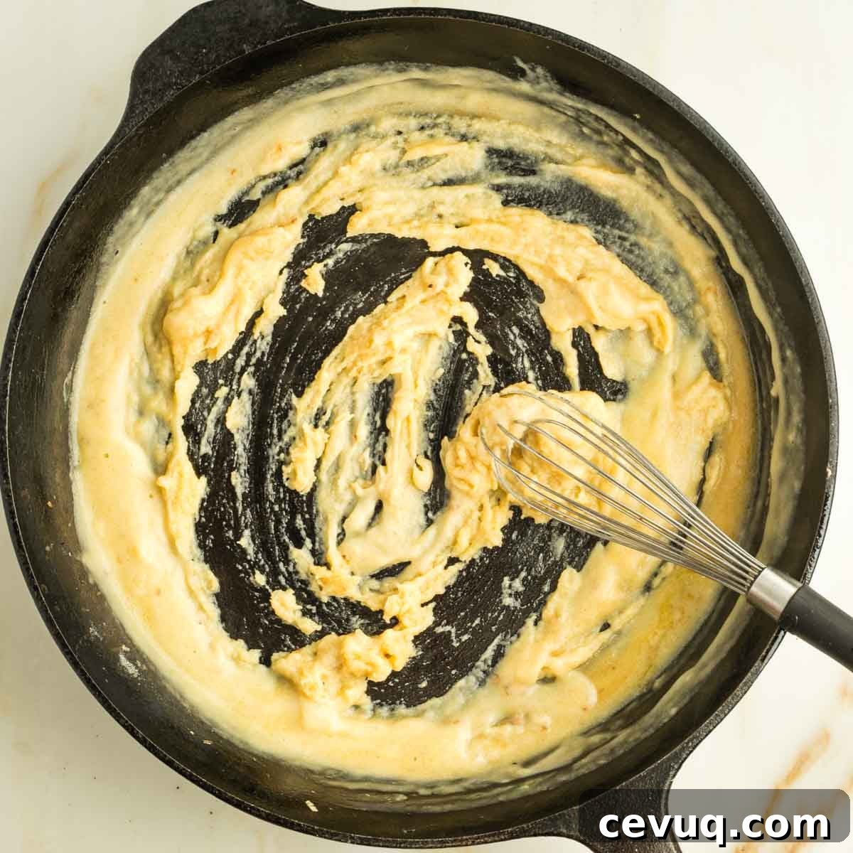 Whisking flour and olive oil into a paste in a cast iron skillet.