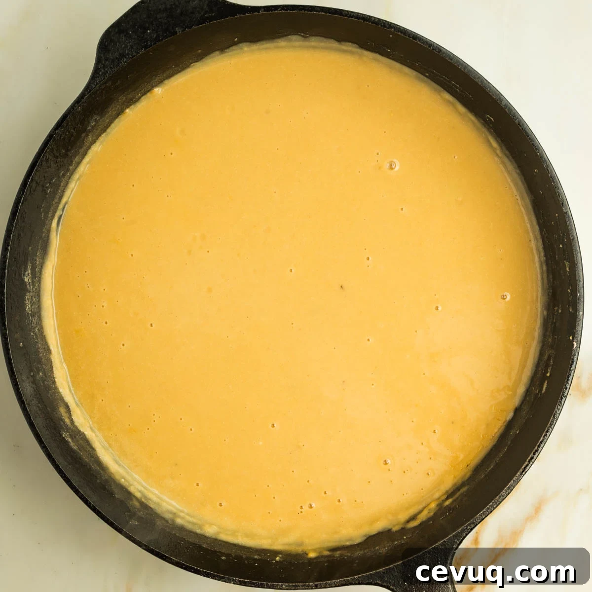 Creamy orangish yellow sauce in a cast iron skillet.