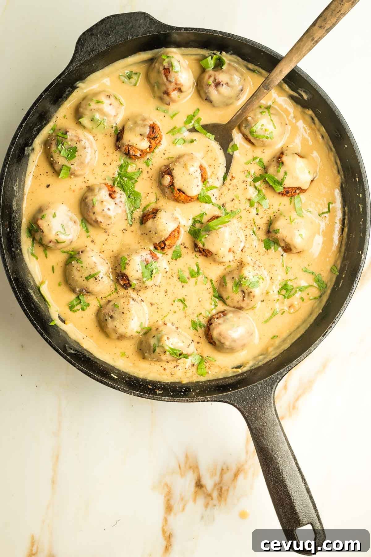 Vegan Swedish meatballs in a mustardy creamy sauce, all inside a cast iron skillet.