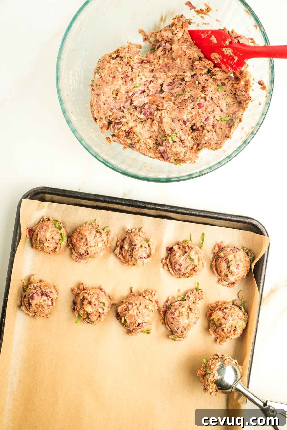 Small cookie scoop portioning out vegan Swedish meatballs from batter in a glass bowl.