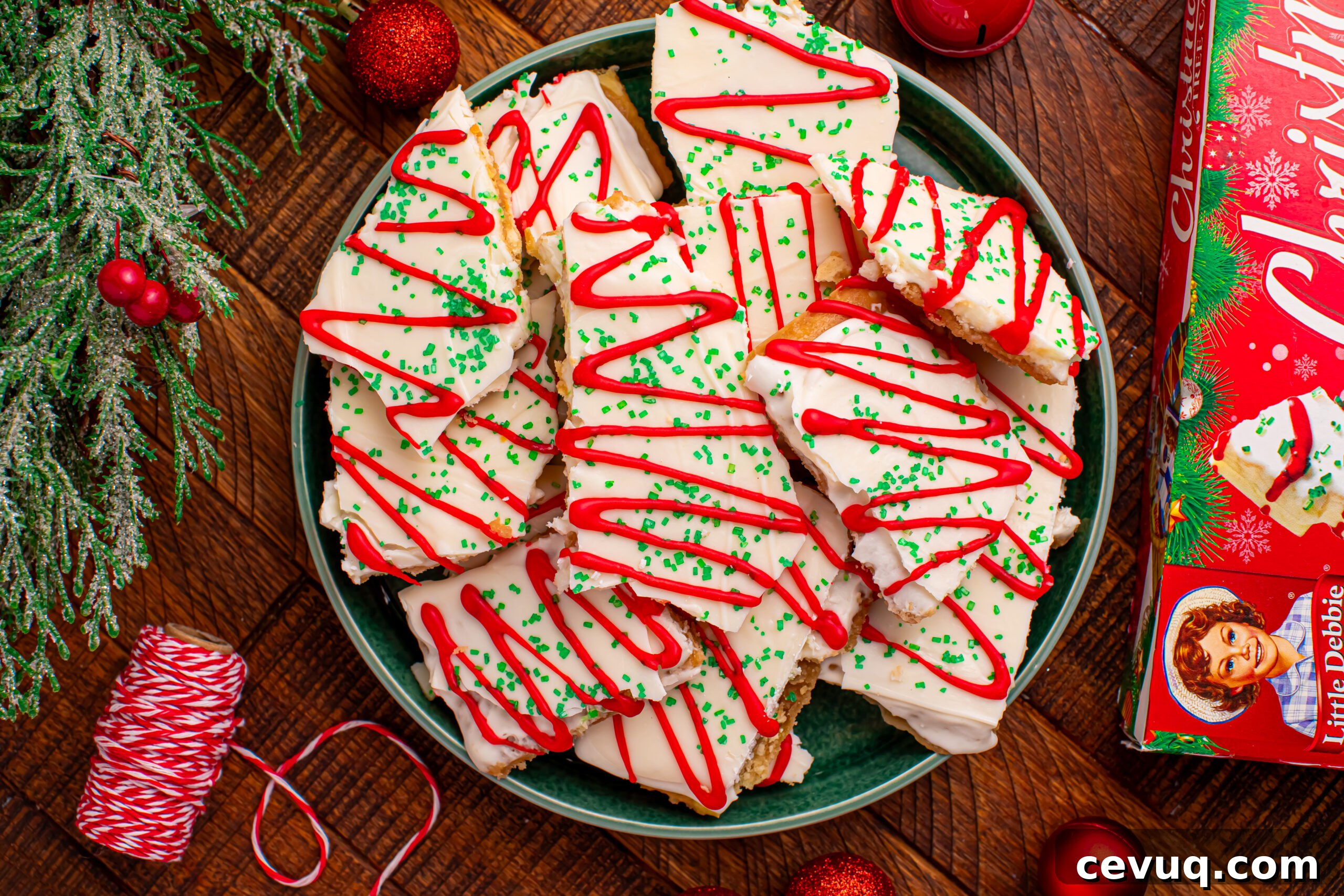 Overhead shot of the Christmas Tree Crack piled on a green serving platter on a dark wood table surrounded by christmas decorations